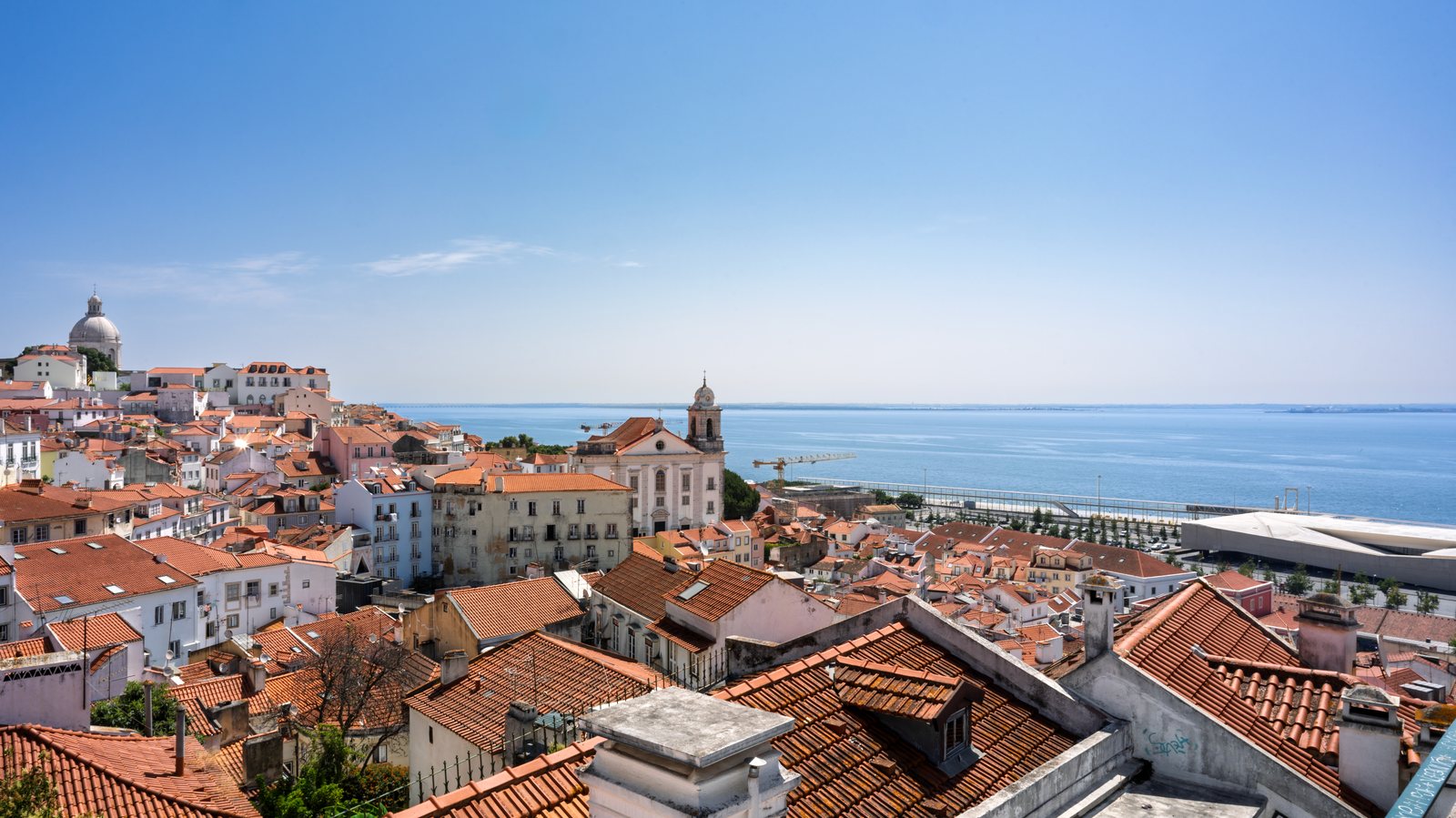 Oranje daken van de Alfama-wijk in Lissabon met uitzicht op de Taag