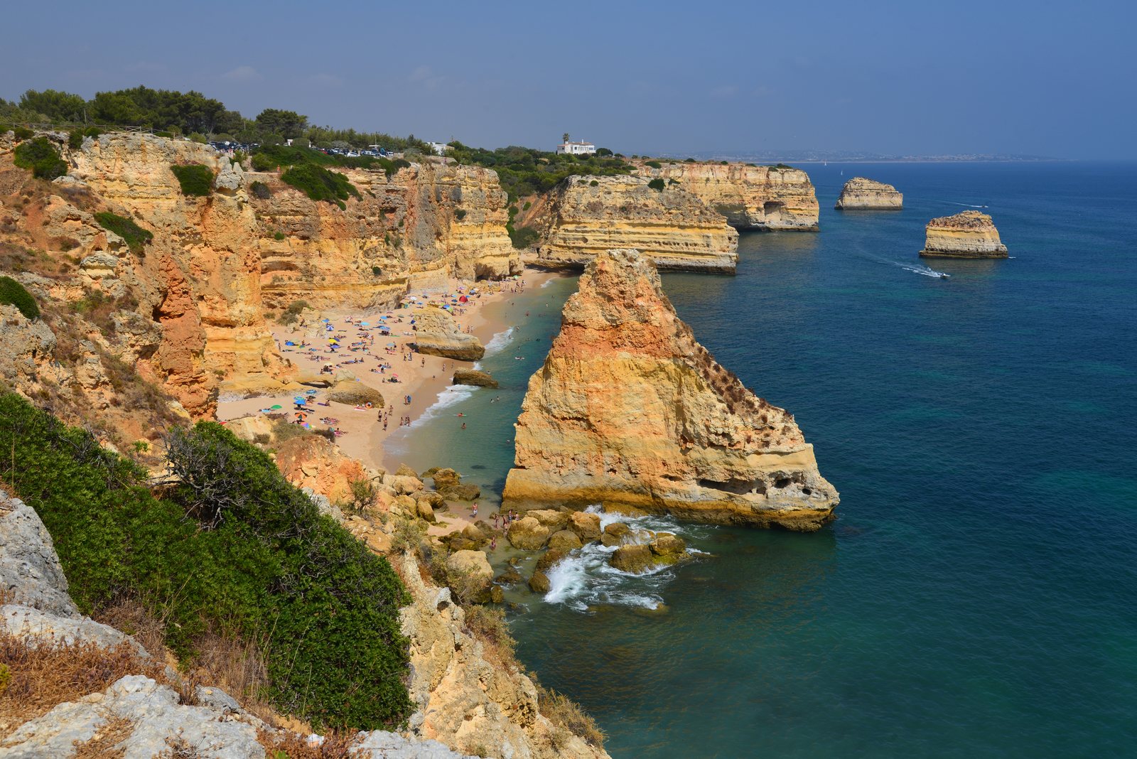 Goudkleurige kliffen en een klein strand met badgasten aan de Algarve-kust